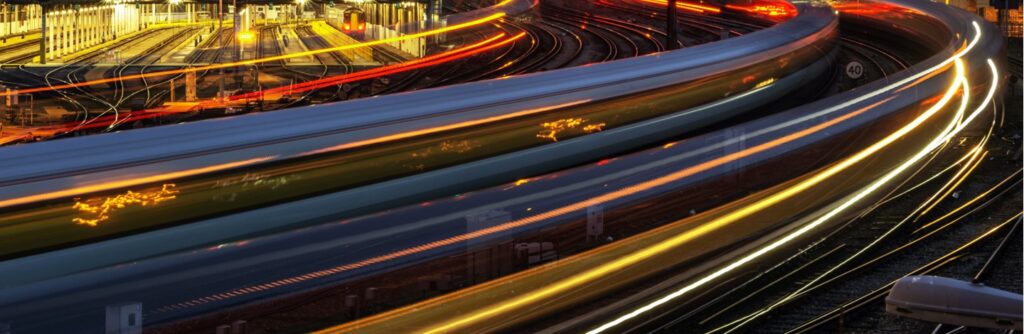 Blurred, high speed passenger train in motion on railroad at night.